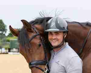 Jezz Palmer standing beside an Anmore Dressage horse wearing riding attire